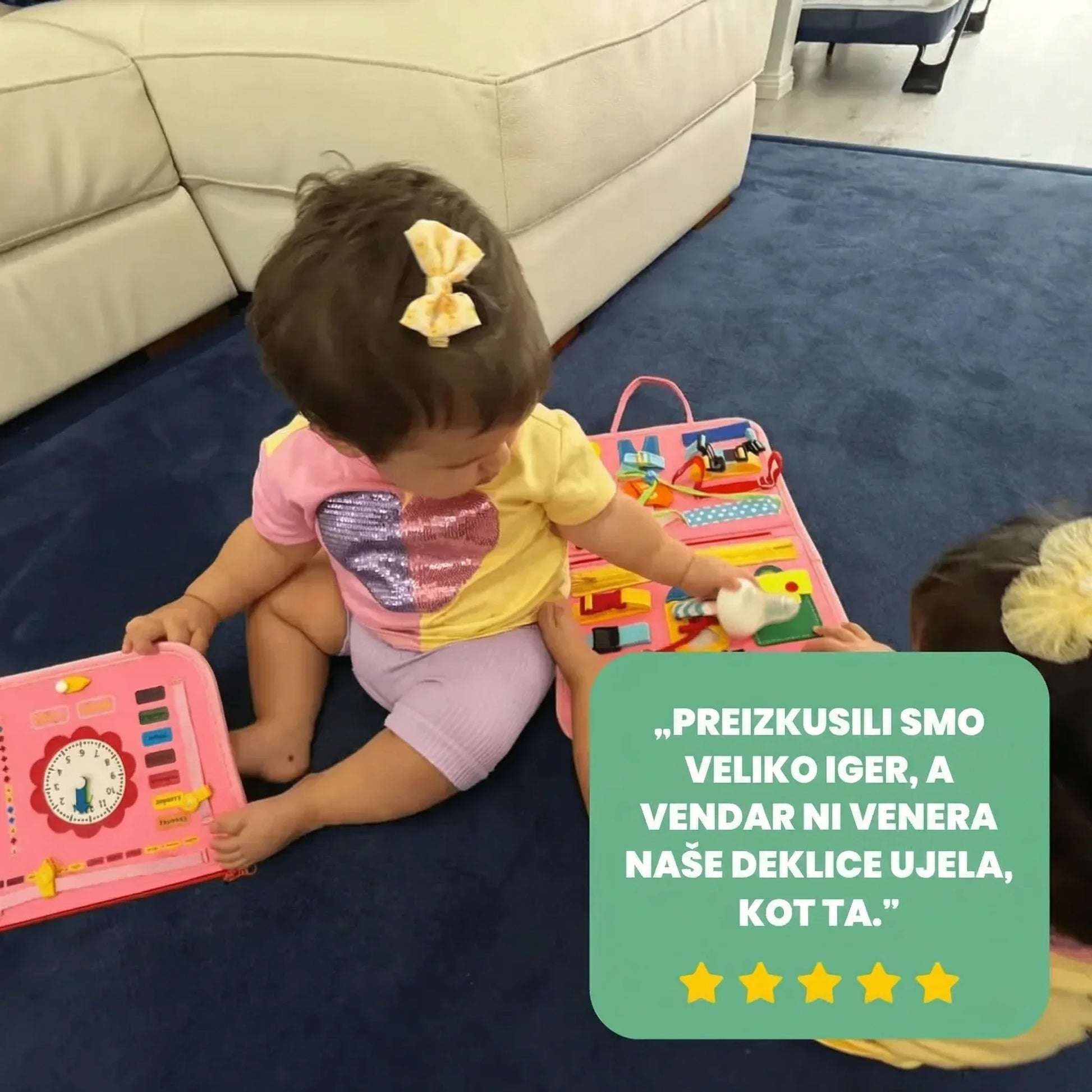 Mnenje zadovoljne stranke s sliko deklice, ki se igra s Kinderspeech senzorično torbo, in besedilom o tem, kako igrača pritegne otrokovo pozornost.